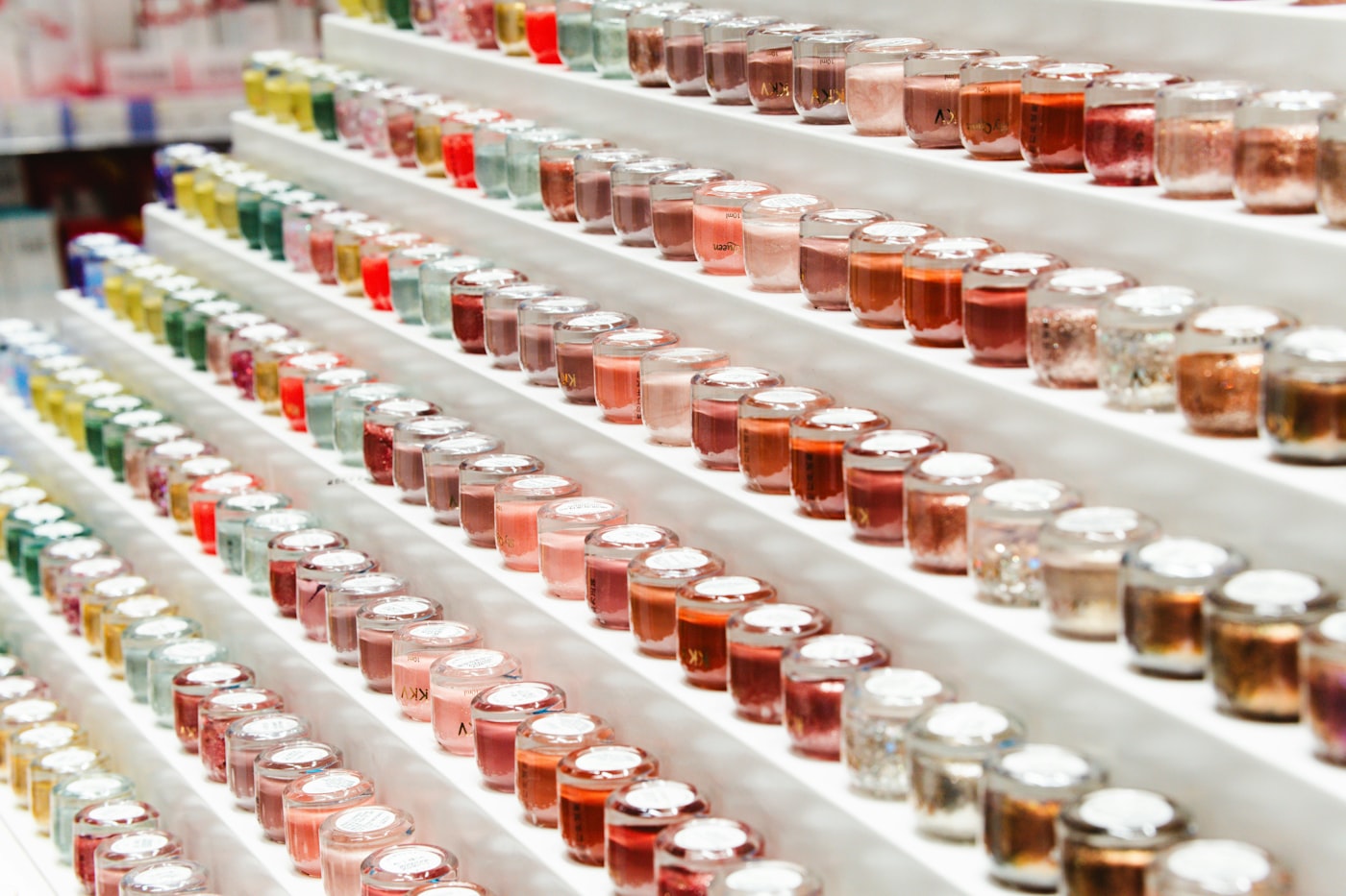 A wall of nail polish bottles in dozens of shades, arranged by colour